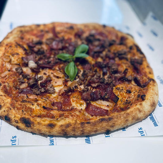 Small pizza with toppings on a white surface