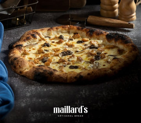 Pizza with various toppings on a dark surface, featuring the 'maillard's Artisanal Bread' brand.