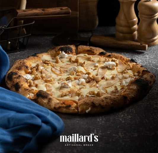 Pizza with toppings on a stone surface, with 'maillard's' branding.