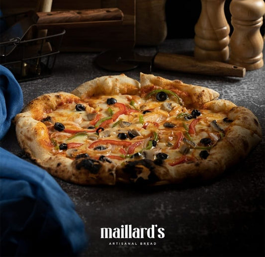 Vegetable pizza on a dark surface with 'maillard's Artisanal Bread' branding.